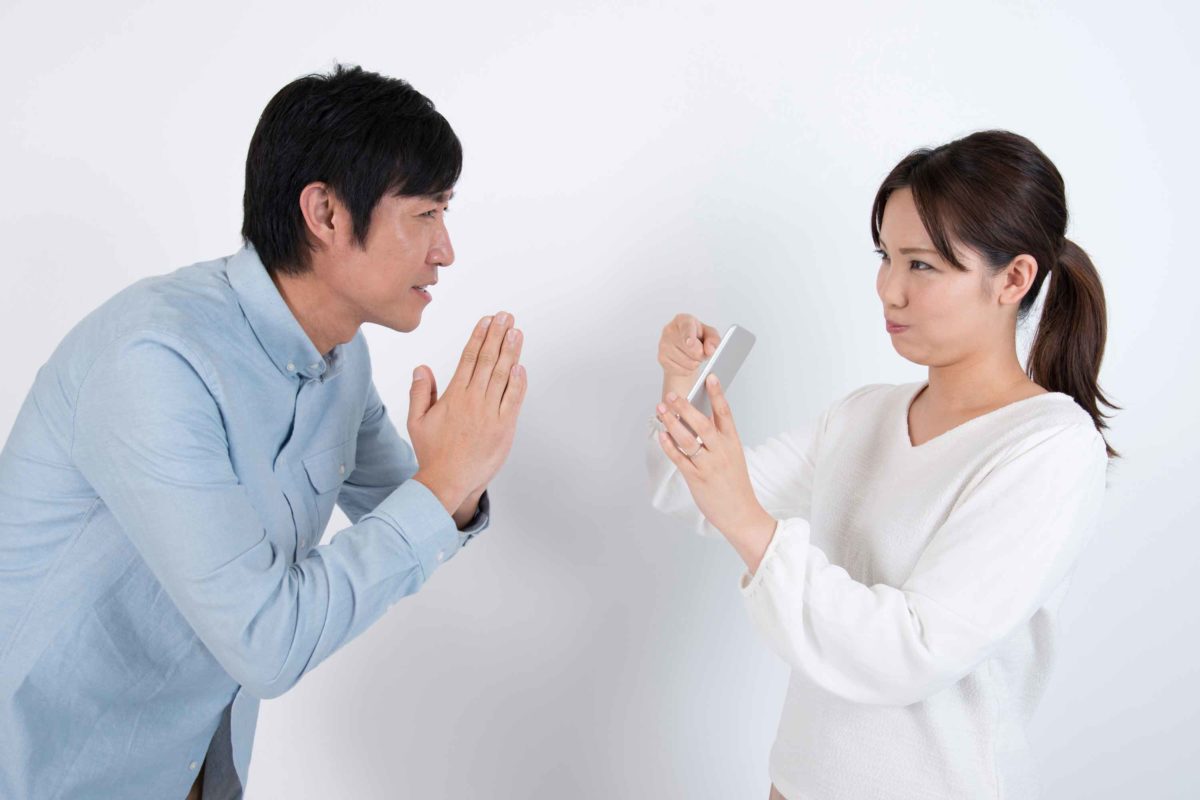 男性にスマホを見せて怒る女性