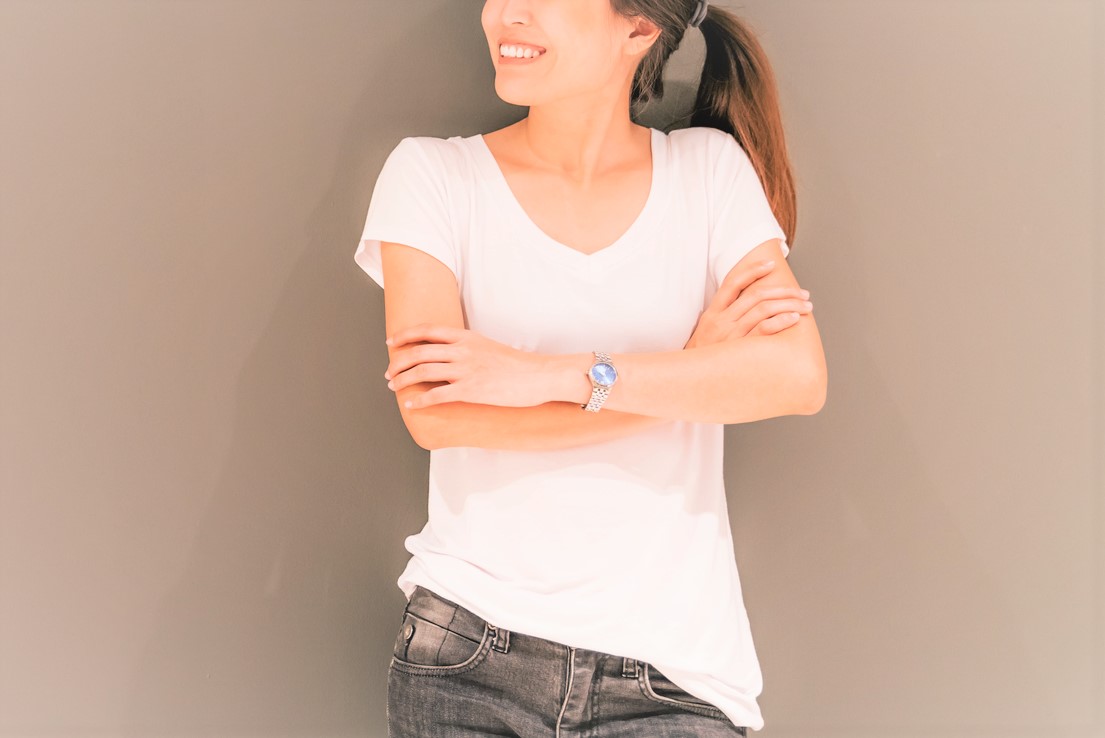 腕を組む女性 Beautiful Asian girl standing on grey wall background, looking