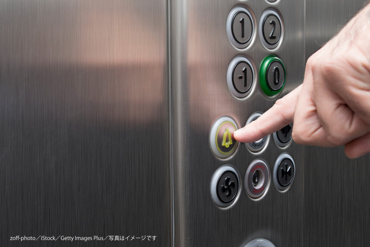 エレベーターのボタンを押す男性